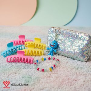 مجموعه‌ای شاد و بازیگوش از گیره‌های مو رنگارنگ، جاکلیدی کارتونی و کیف پولک‌دار مخملی، بازتابی از نوستالژی دهه ۲۰۰۰ و ترندهای جذاب لوازم جانبی مد ۲۰۲۵.